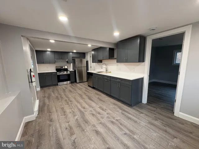 a large kitchen with a large counter top a sink and stainless steel appliances