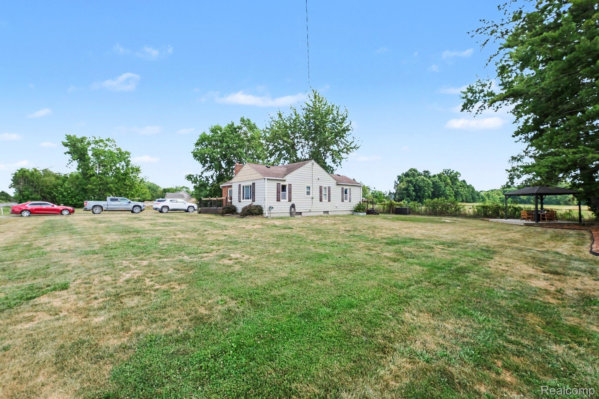 5409 Baldwin Road Swartz Creek, MI 48473 - Photo 25 of 27 Expansive backyard featuring a gazebo with a concrete pad, mature trees, and a detached single-story residence