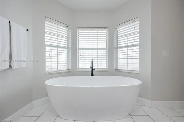 a white bath tub sitting in a bathroom next to a window