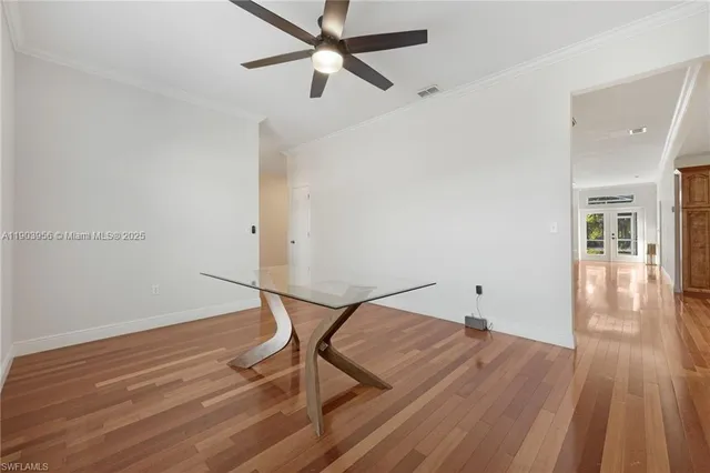 an empty room with wooden floor a ceiling fan and windows