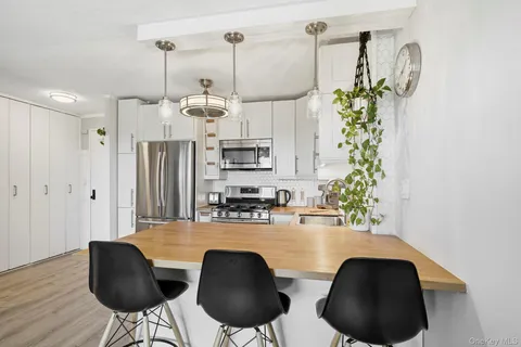 a kitchen with stainless steel appliances a table chairs refrigerator and microwave
