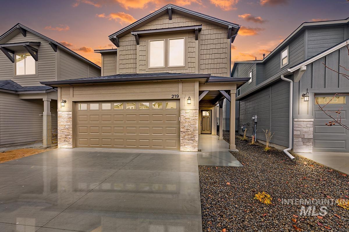 View of front of house with stone siding, concrete driveway, and a garage