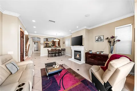 a view of a dining room and livingroom with furniture a rug a flat screen tv and a large window