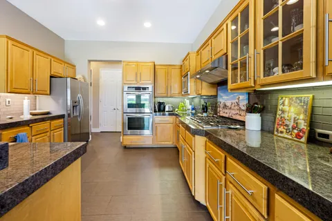a kitchen with stainless steel appliances granite countertop a sink a counter space and living room view