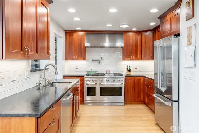 a kitchen with stainless steel appliances granite countertop a sink a stove and a refrigerator