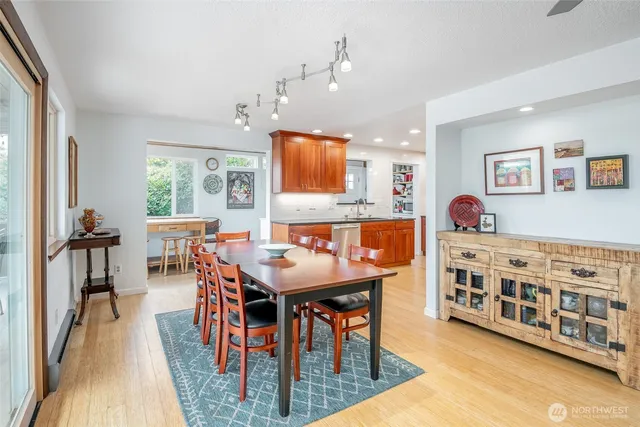 a view of a dining room and livingroom with furniture wooden floor a rug a flat screen tv a rug and a chandelier