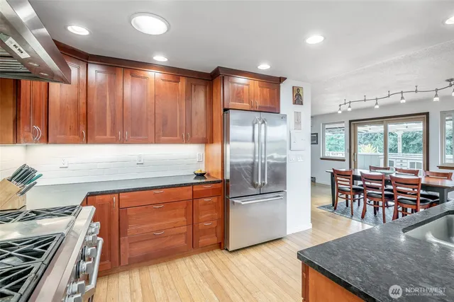a kitchen with stainless steel appliances granite countertop a stove top oven a sink and a refrigerator
