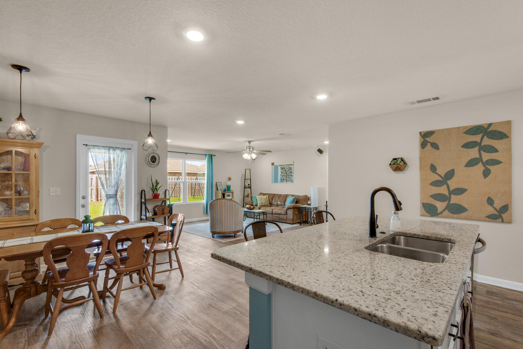 1016 Limpkin Street Crestview, FL 32539 - Photo 29 of 36 a kitchen with granite countertop a dining table chairs and white cabinets