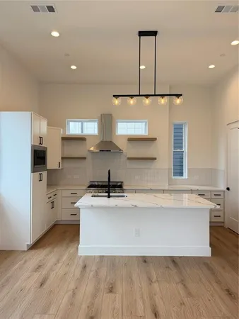 a large kitchen with stainless steel appliances a large counter top a sink a stove and cabinets