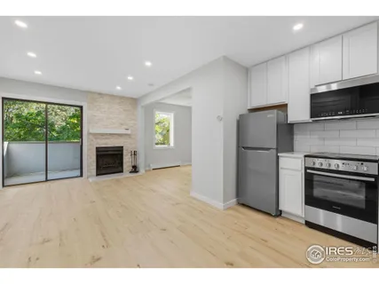 a view of kitchen with stainless steel appliances wooden floor and window