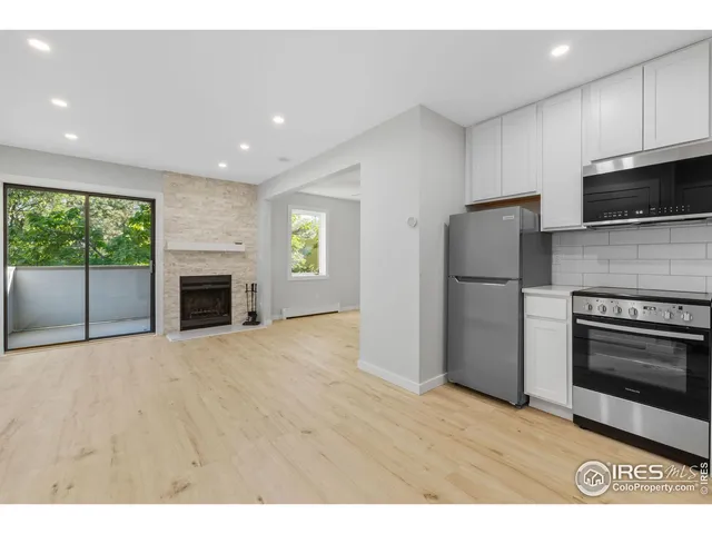 a view of kitchen with stainless steel appliances wooden floor and window