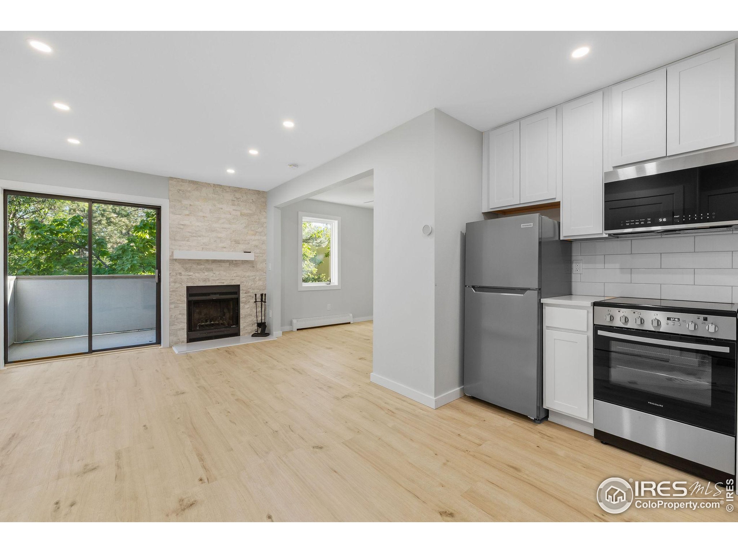 a view of kitchen with stainless steel appliances wooden floor and window