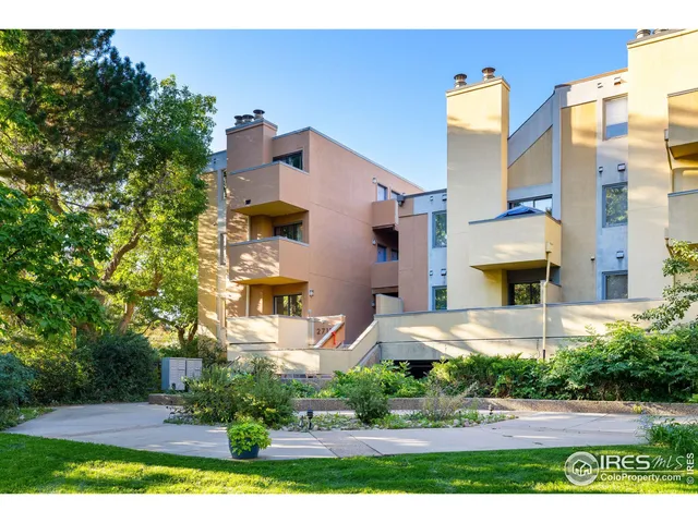 a front view of a multi story residential apartment building with yard and parking