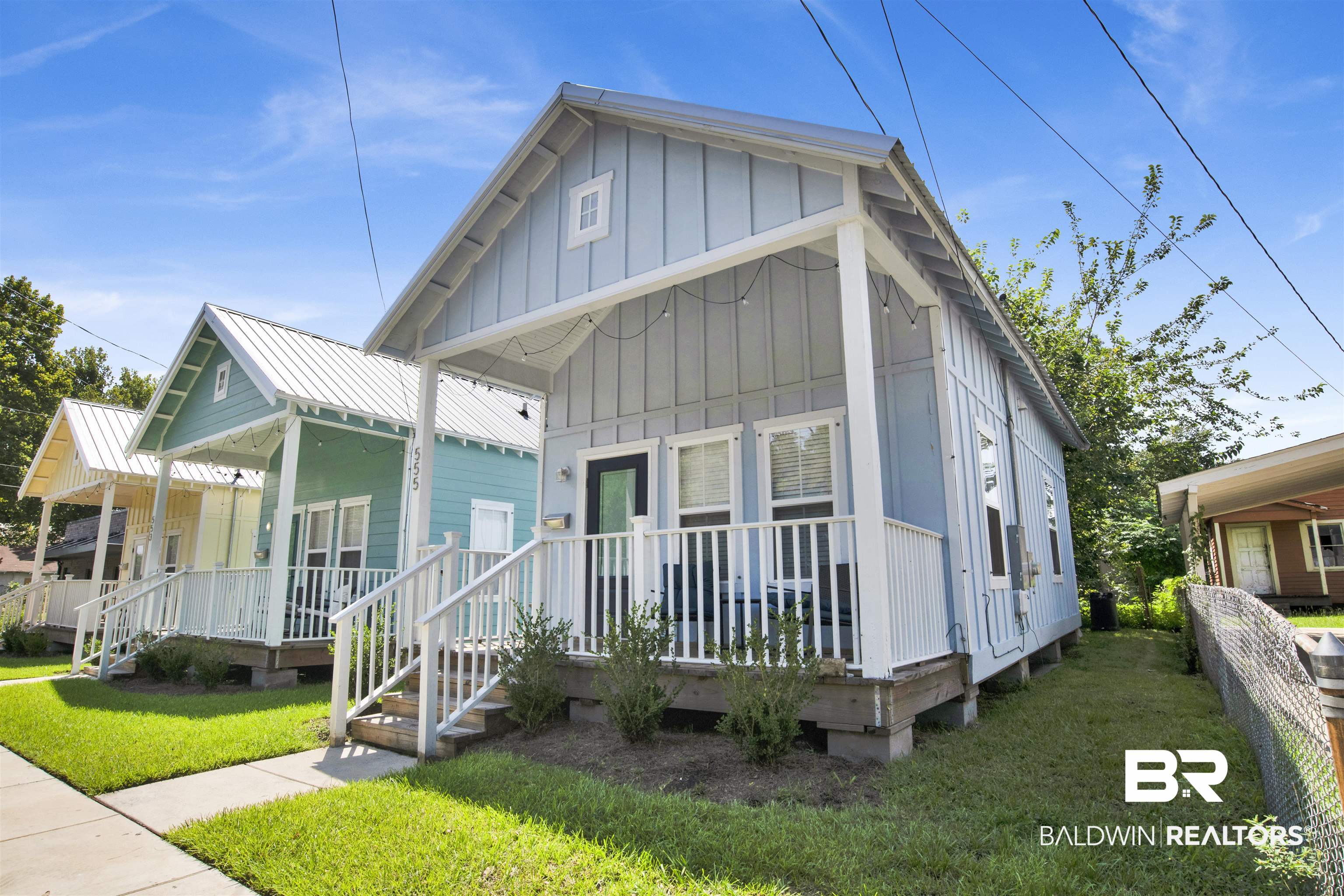 View of front of house with board and batten siding, a front yard, and covered porch