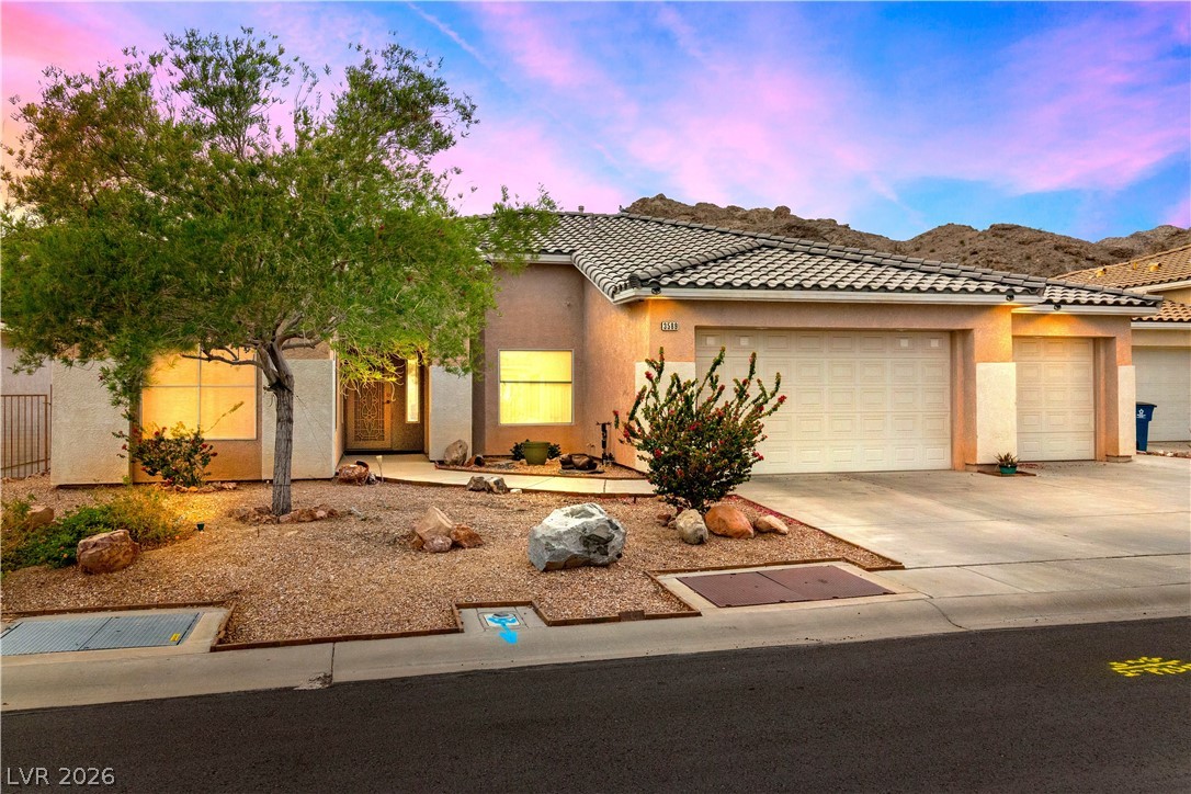 View of front of property featuring mountain views, stucco siding, driveway, and an attached garage