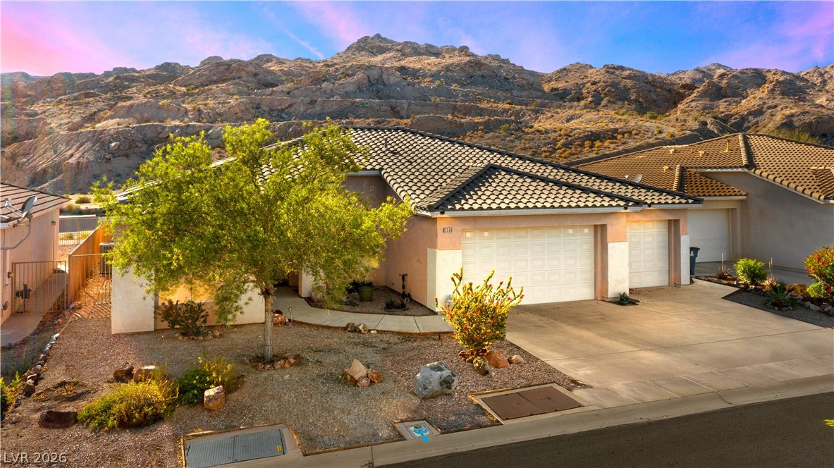 3589 Cottage Canyon Street Laughlin, NV 89029 - Photo 2 of 99 View of front of home with a mountain view, an attached garage, a tile roof, stucco siding, and driveway