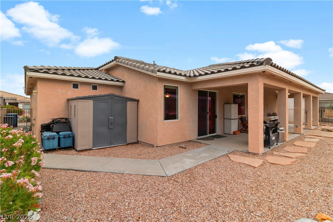 3589 Cottage Canyon Street Laughlin, NV 89029 - Photo 66 of 99 Rear view of house with a storage shed, stucco siding, a tile roof, and a patio