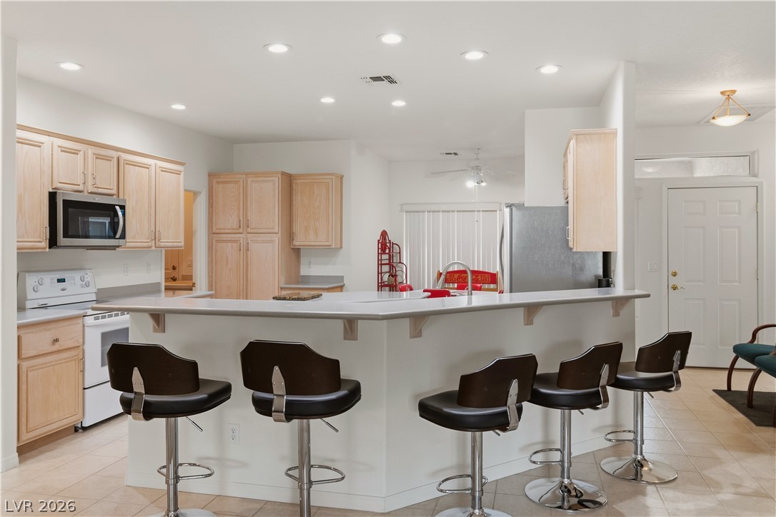 3589 Cottage Canyon Street Laughlin, NV 89029 - Photo 7 of 99 Kitchen featuring light wood finish cabinets, a breakfast bar area, stainless steel appliances, light countertops, and a peninsula