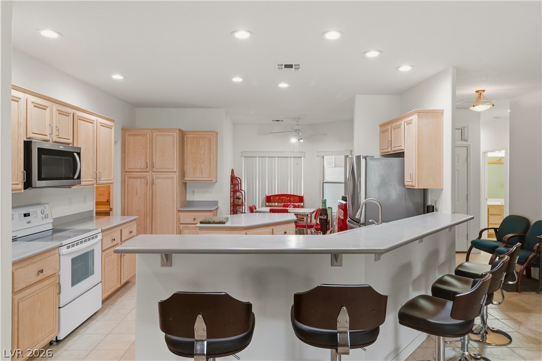 3589 Cottage Canyon Street Laughlin, NV 89029 - Photo 8 of 99 Kitchen with light wood finish cabinetry, stainless steel appliances, recessed lighting, light countertops, and a kitchen island