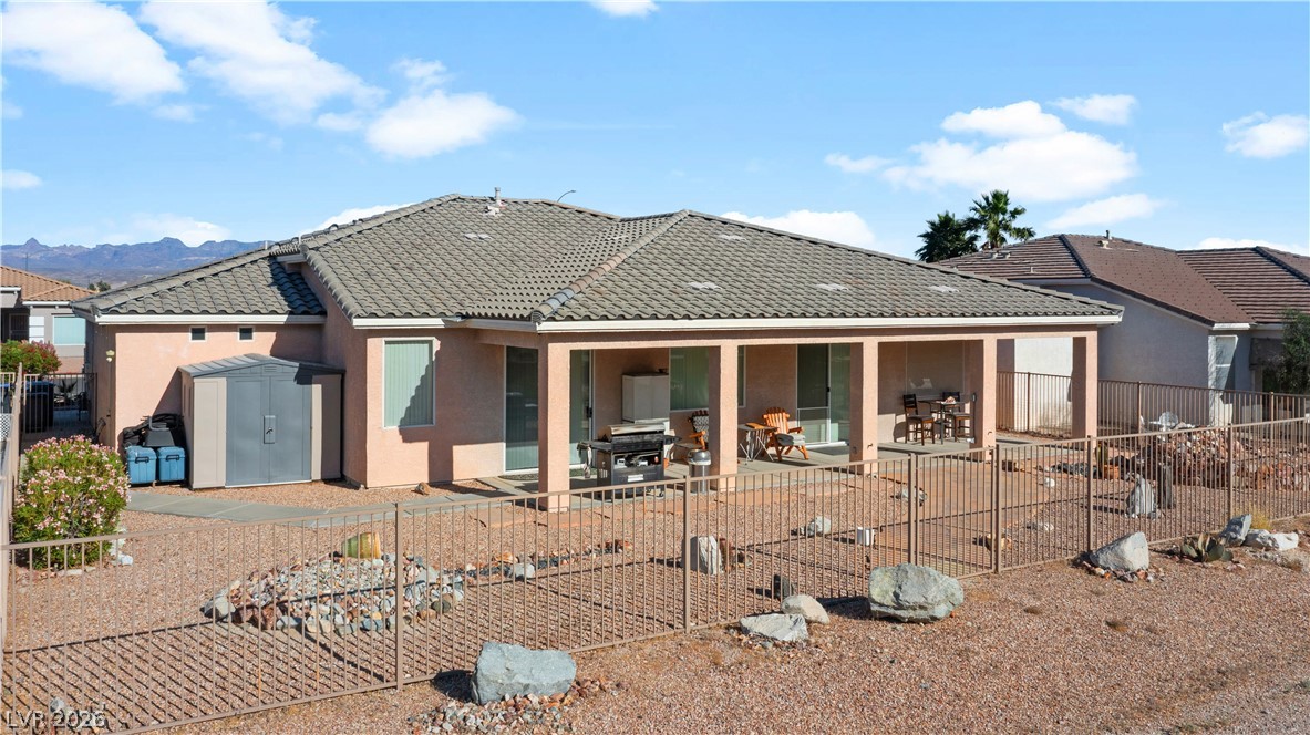 3589 Cottage Canyon Street Laughlin, NV 89029 - Photo 86 of 99 Rear view of house featuring a patio area, a fenced backyard, a tiled roof, stucco siding, and a shed