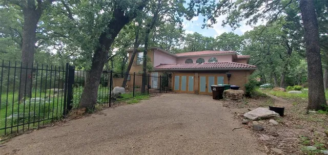 a view of a patio with table and chairs under an umbrella with large trees