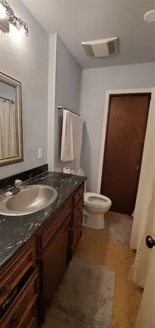 a bathroom with a granite countertop sink and a toilet