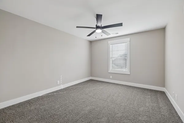 an empty room with a window and ceiling fan