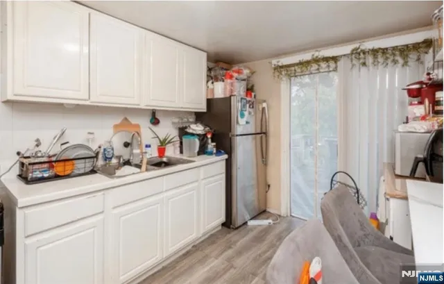 a kitchen with stainless steel appliances granite countertop a refrigerator and a white cabinets