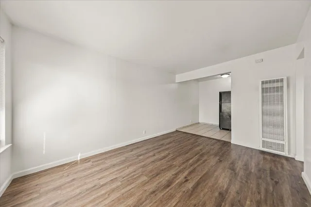 a view of an empty room with wooden floor and closet