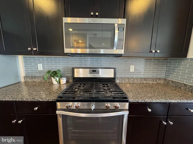 a view of a kitchen with wooden floor a ceiling fan and windows