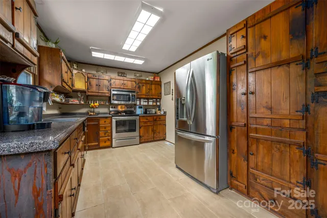 a kitchen with stainless steel appliances granite countertop a refrigerator a stove and a sink with wooden floor