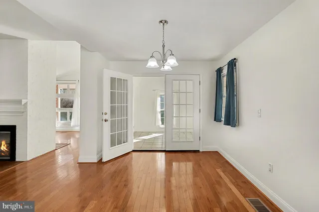 an empty room with wooden floor chandelier and windows