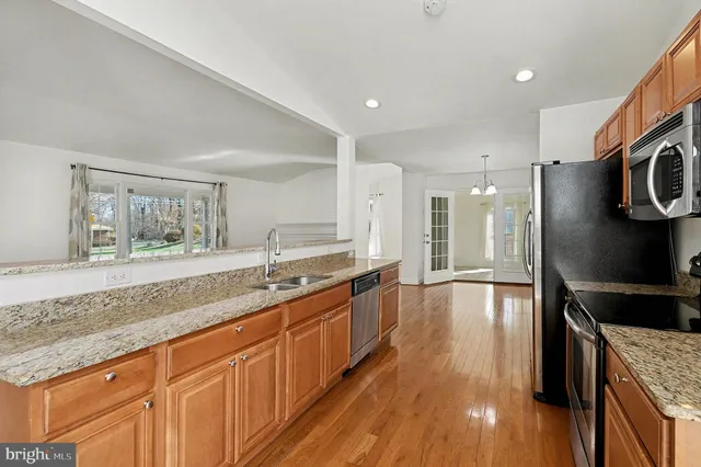 a large kitchen with stainless steel appliances granite countertop a lot of counter space and wooden floor