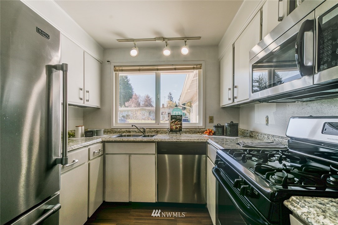 16618 124th Avenue Southeast Renton, WA 98058 - Photo 8 of 21 a kitchen with stainless steel appliances granite countertop a sink stove refrigerator and cabinets