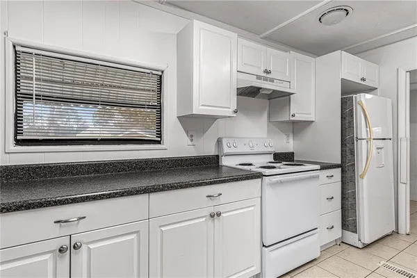 a kitchen with granite countertop white cabinets and white appliances