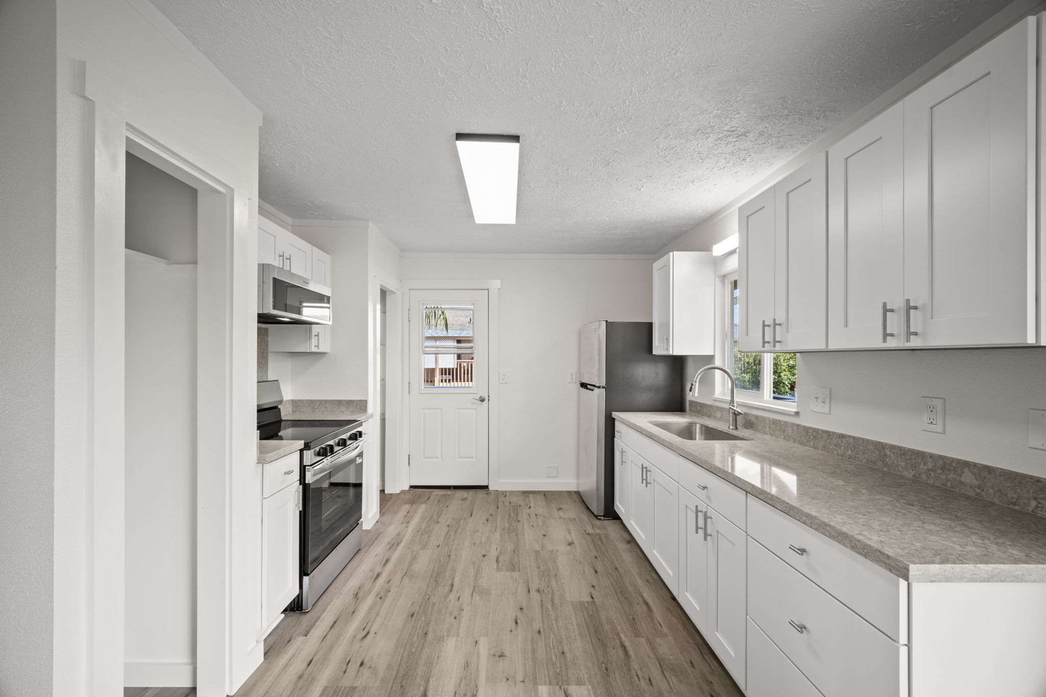 4431 Iona Road Hanapepe, HI 96705 - Photo 3 of 20 a kitchen with white cabinets stainless steel appliances and wooden floor