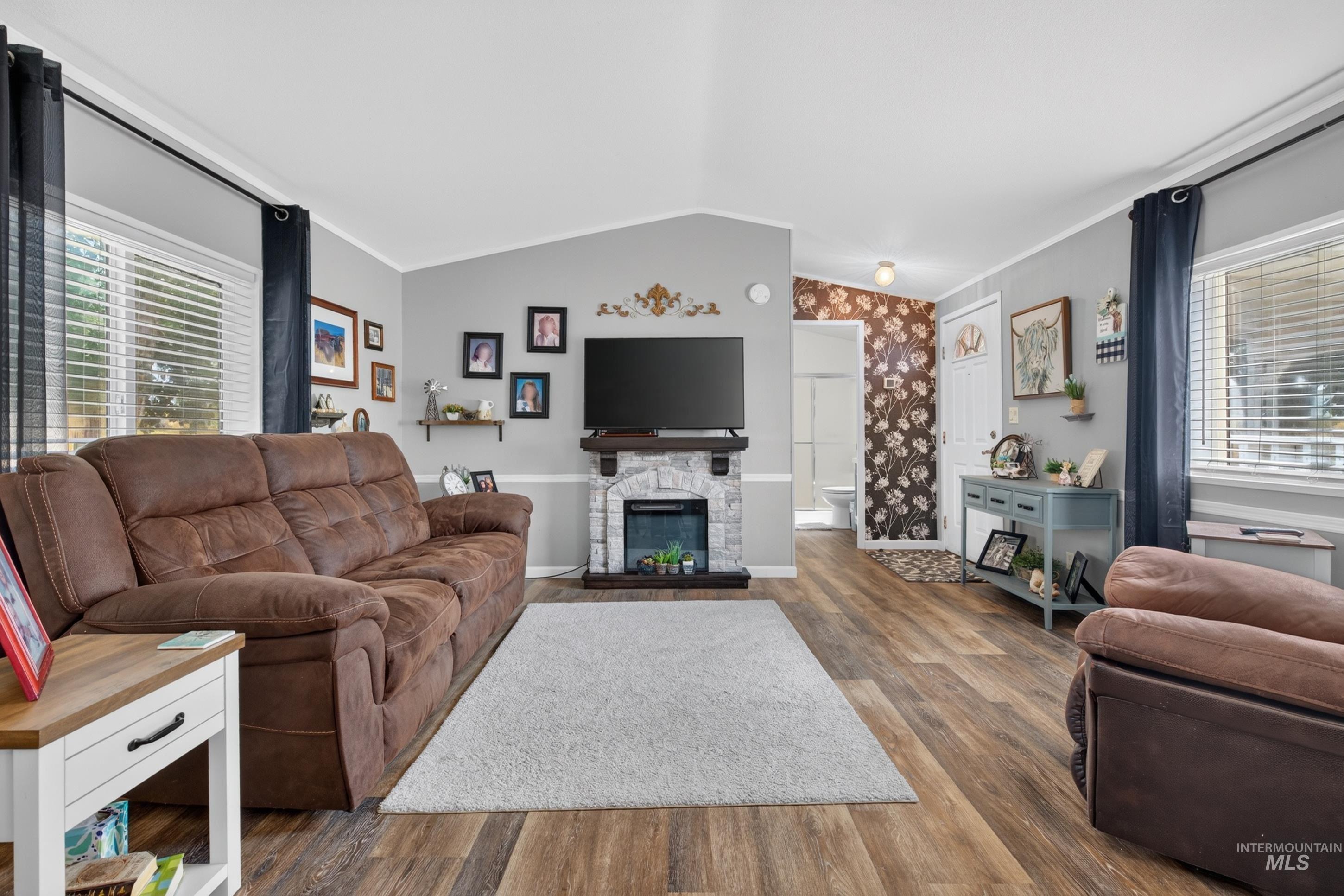 7417 Map Rock Road Caldwell, ID 83607 - Photo 21 of 32 Spacious living area featuring wood-finish flooring, a stone-clad fireplace with a built-in mantel, and multiple windows