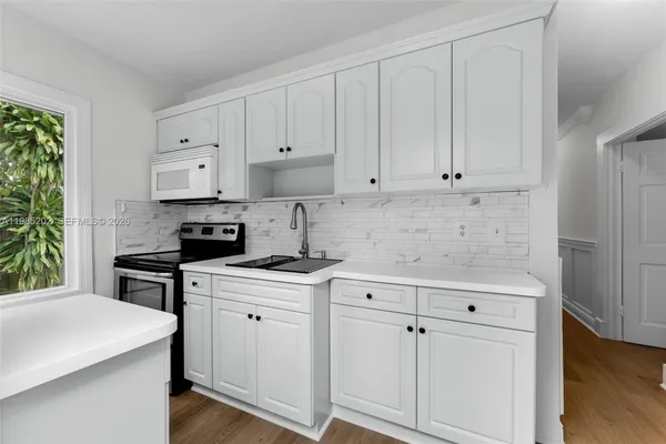 a large white kitchen with sink and stainless steel appliances