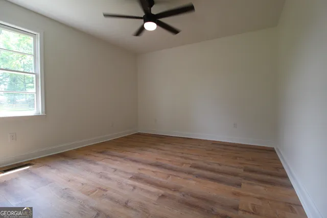 an empty room with a window and a ceiling fan