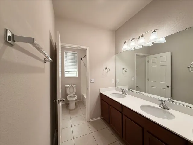 a spacious bathroom with a double vanity sink toilet and a mirror