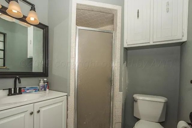 a bathroom with a toilet sink vanity and granite