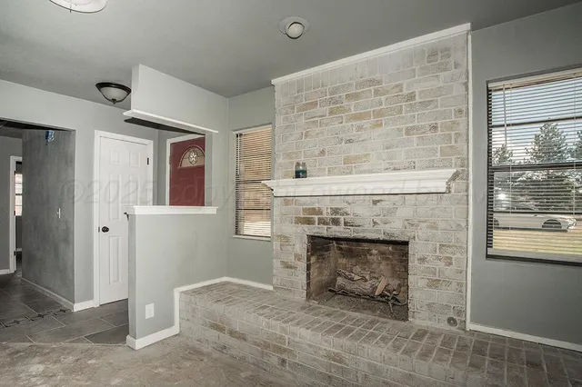 an empty room with windows and fireplace