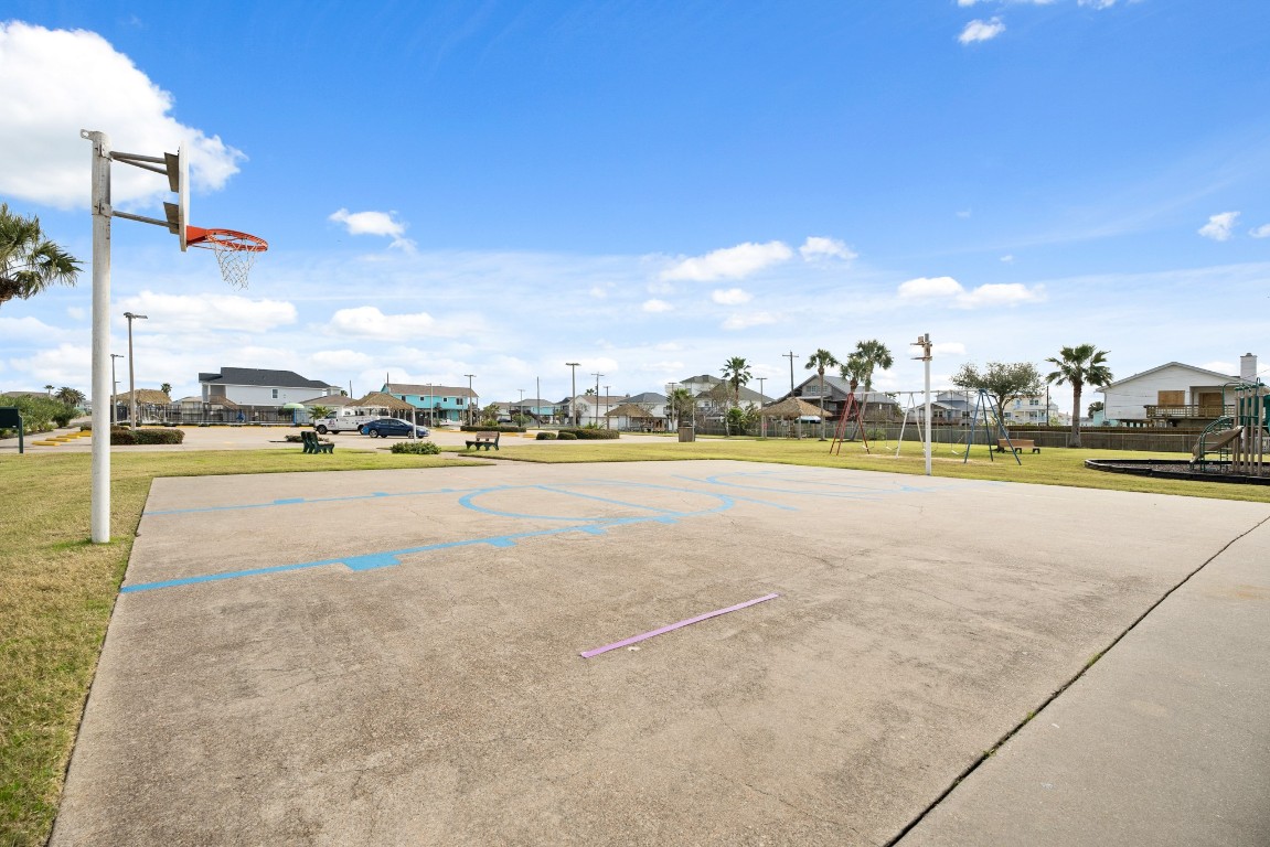 16507 Captain Kidd Road Jamaica Beach, TX 77554 - Photo 22 of 37 Community recreational area with a basketball court, playground equipment, and picnic benches. It's a spacious outdoor space, ideal for family activities.