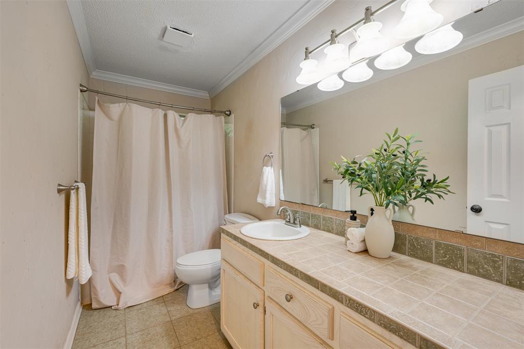 248 Butternut Lane Powderly, TX 75473 - Photo 30 of 40 a bathroom with a granite countertop sink a toilet and a large mirror