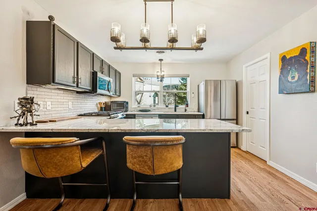 a kitchen with stainless steel appliances granite countertop a sink a stove window and chairs