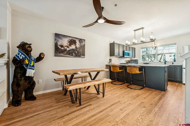 a dining room with wooden floor a chandelier a wooden table and chairs