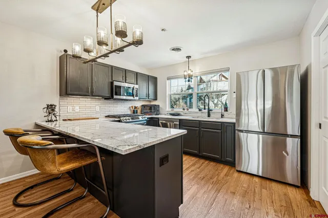 a kitchen with stainless steel appliances granite countertop a sink refrigerator and cabinets