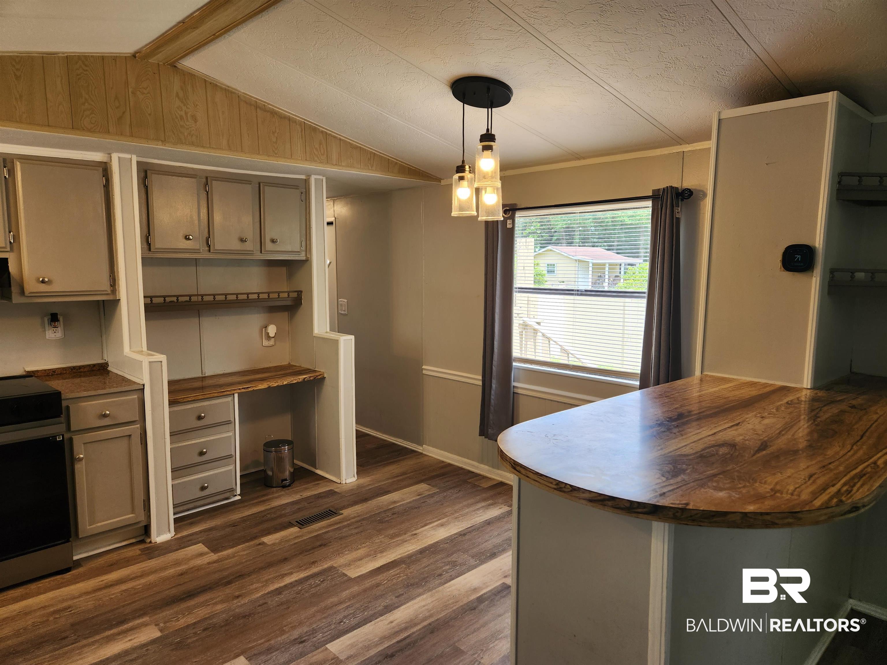 23051 Fritz Lane Foley, AL 36535 - Photo 20 of 26 Kitchen area featuring wood-finish flooring, a breakfast bar with a wood-look countertop, built-in desk space, and a contemporary pendant light fixture