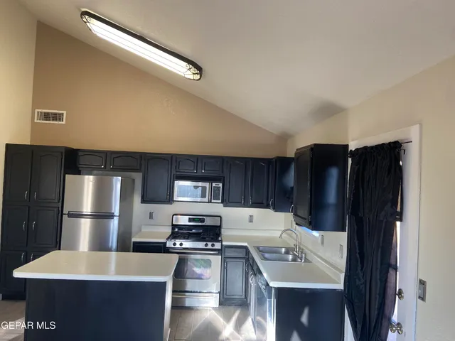 a kitchen with kitchen island stainless steel appliances a sink and counter space