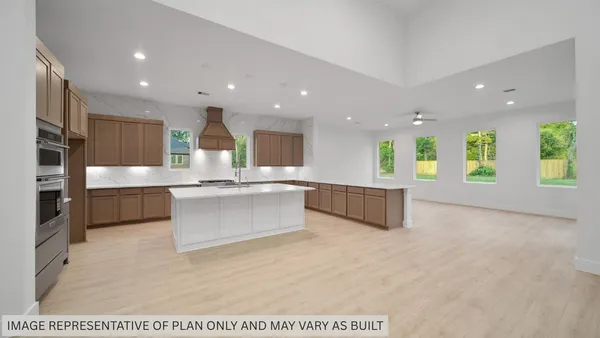 a large white kitchen with a large counter top stainless steel appliances and cabinets